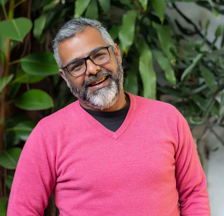man smiling in a pink sweater